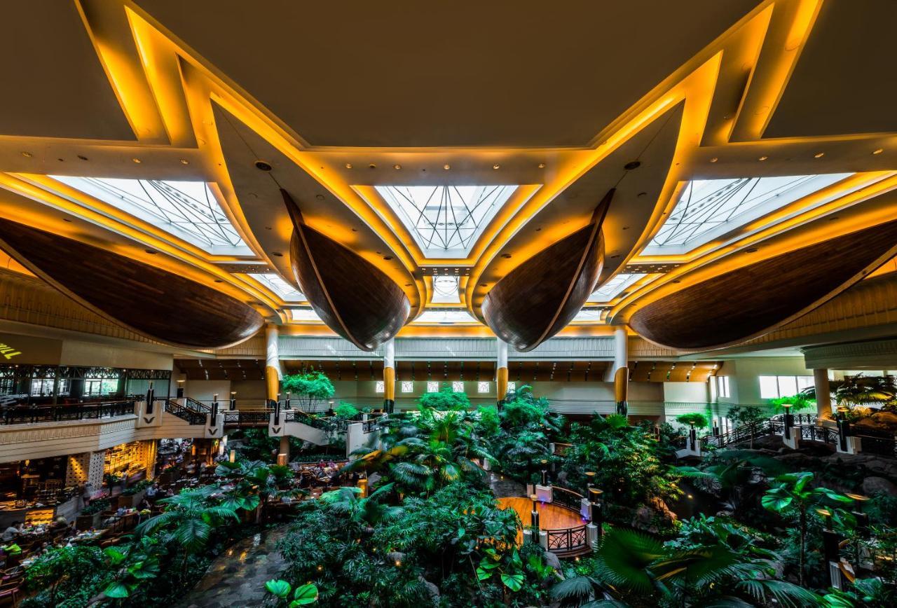 Hotel Grand Hyatt Dubai Esterno foto The photo depicts the interior of a grand building, likely a hotel or resort, featuring a stunning atrium. The space is characterized by large, elegantly designed boat-shaped structures suspended from the ceiling, which are illuminated by warm light.