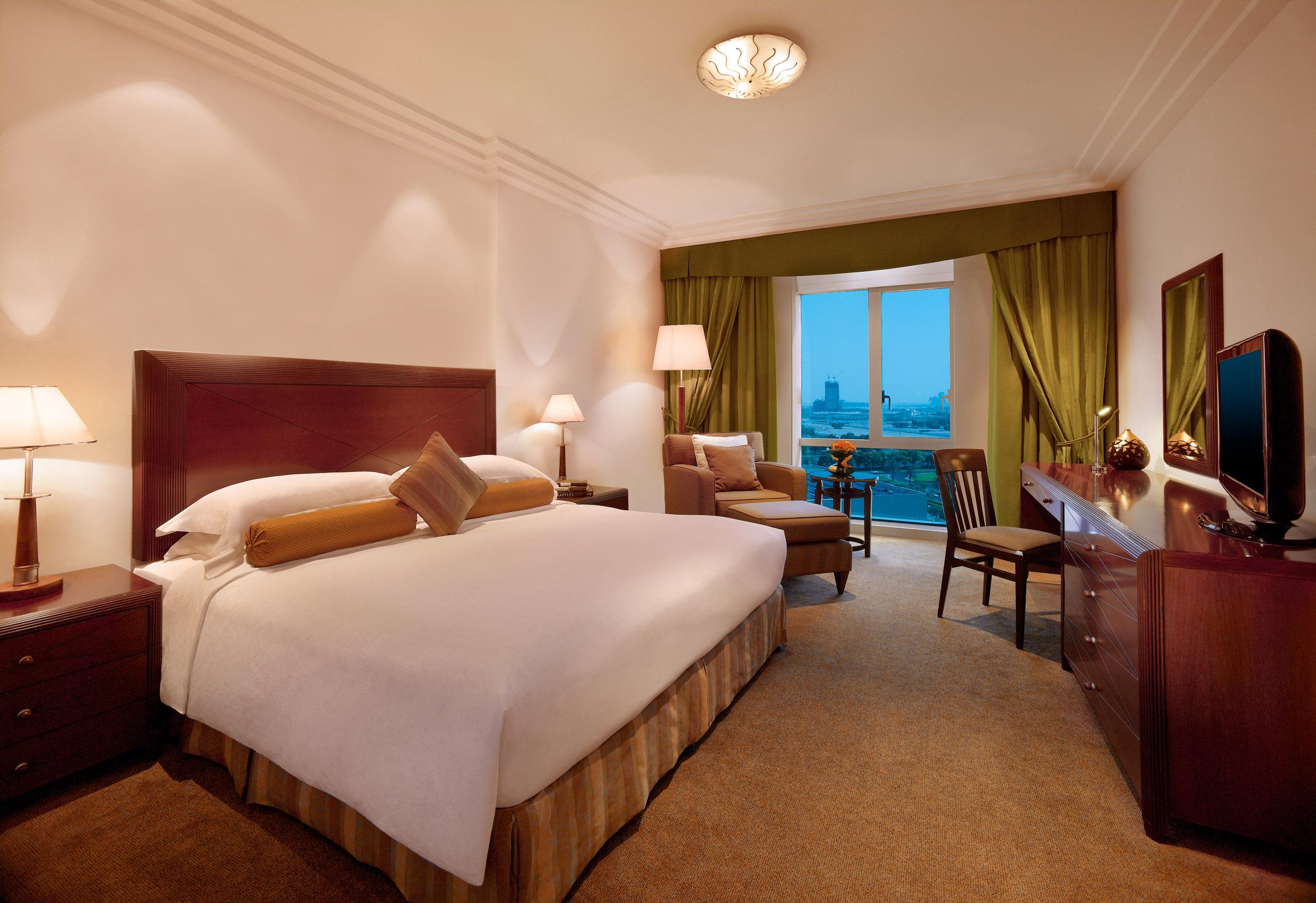 Hotel Grand Hyatt Dubai Esterno foto The photo shows a well-furnished hotel room. It features a large bed with a light-colored comforter and decorative pillows. The walls are painted in a soft color, and there are lamps on either side of the bed. A cozy seating area is present, which in