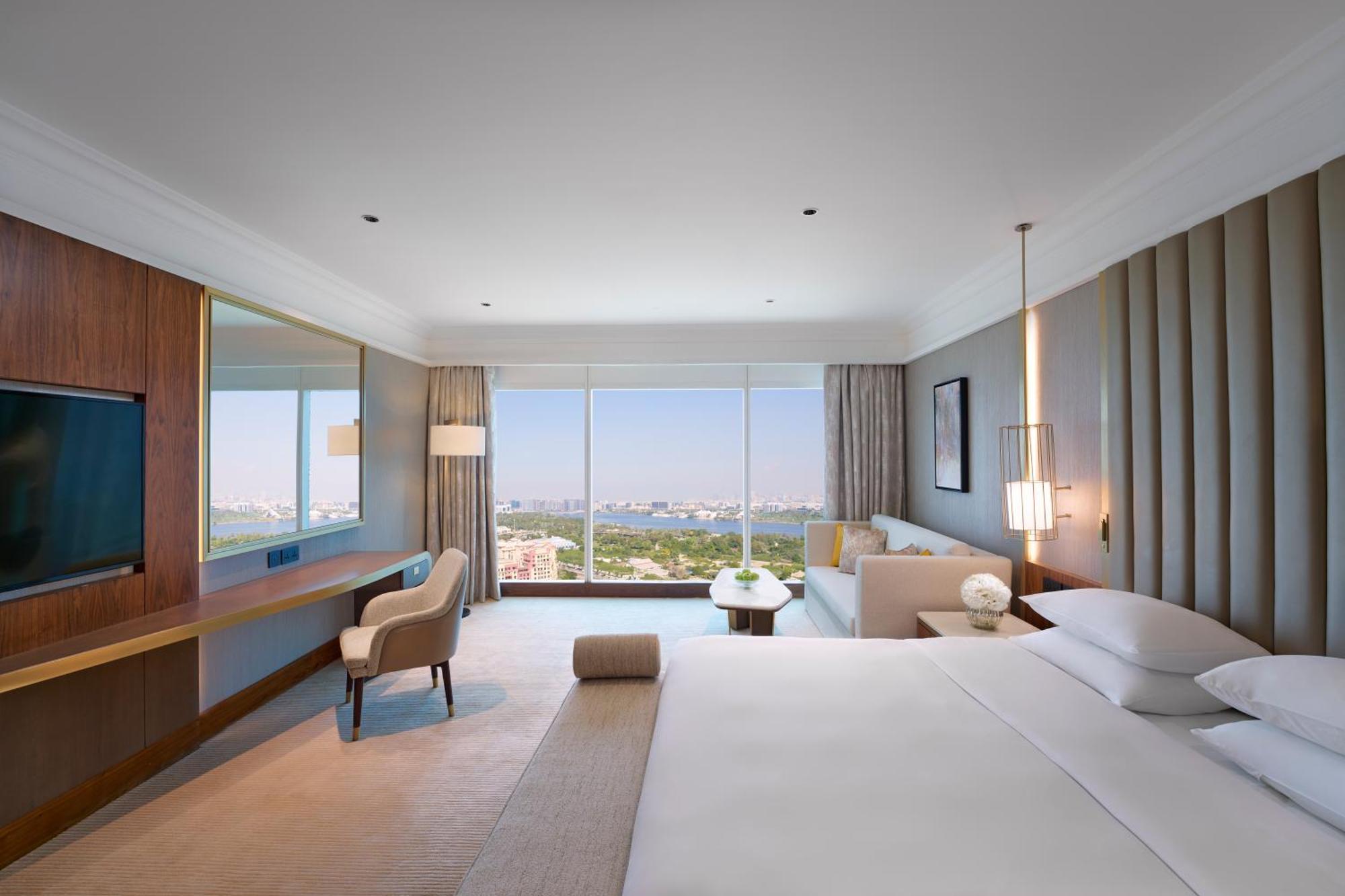 Hotel Grand Hyatt Dubai Esterno foto The photo depicts a modern hotel room featuring a spacious and elegantly designed interior. Key elements include:

- A large bed with crisp white linens, positioned against a wall.
- A comfortable chair and a small side table strategically placed nea