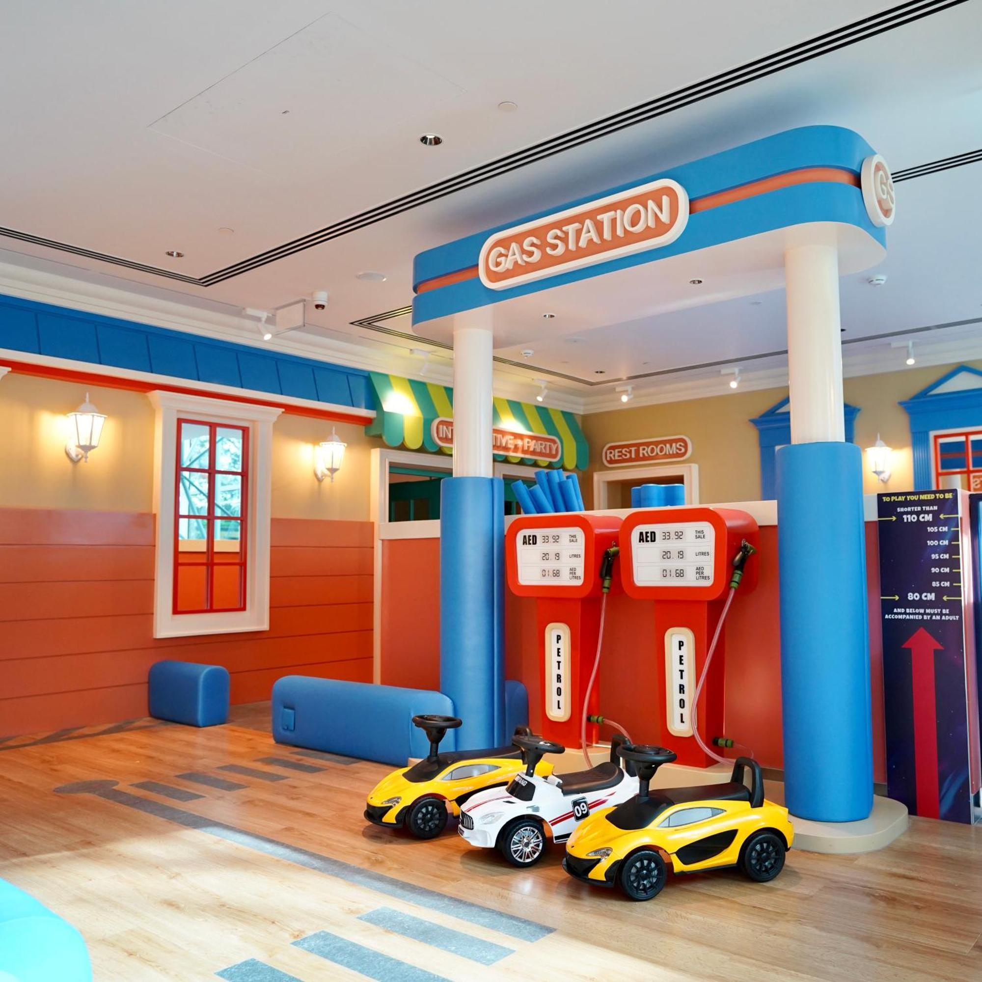 Hotel Grand Hyatt Dubai Esterno foto The photo shows a brightly colored play area designed to resemble a gas station. There are two large gas pumps with a "GAS STATION" sign above them, set against a cheerful backdrop. The walls are painted in vibrant colors, with features like windows 
