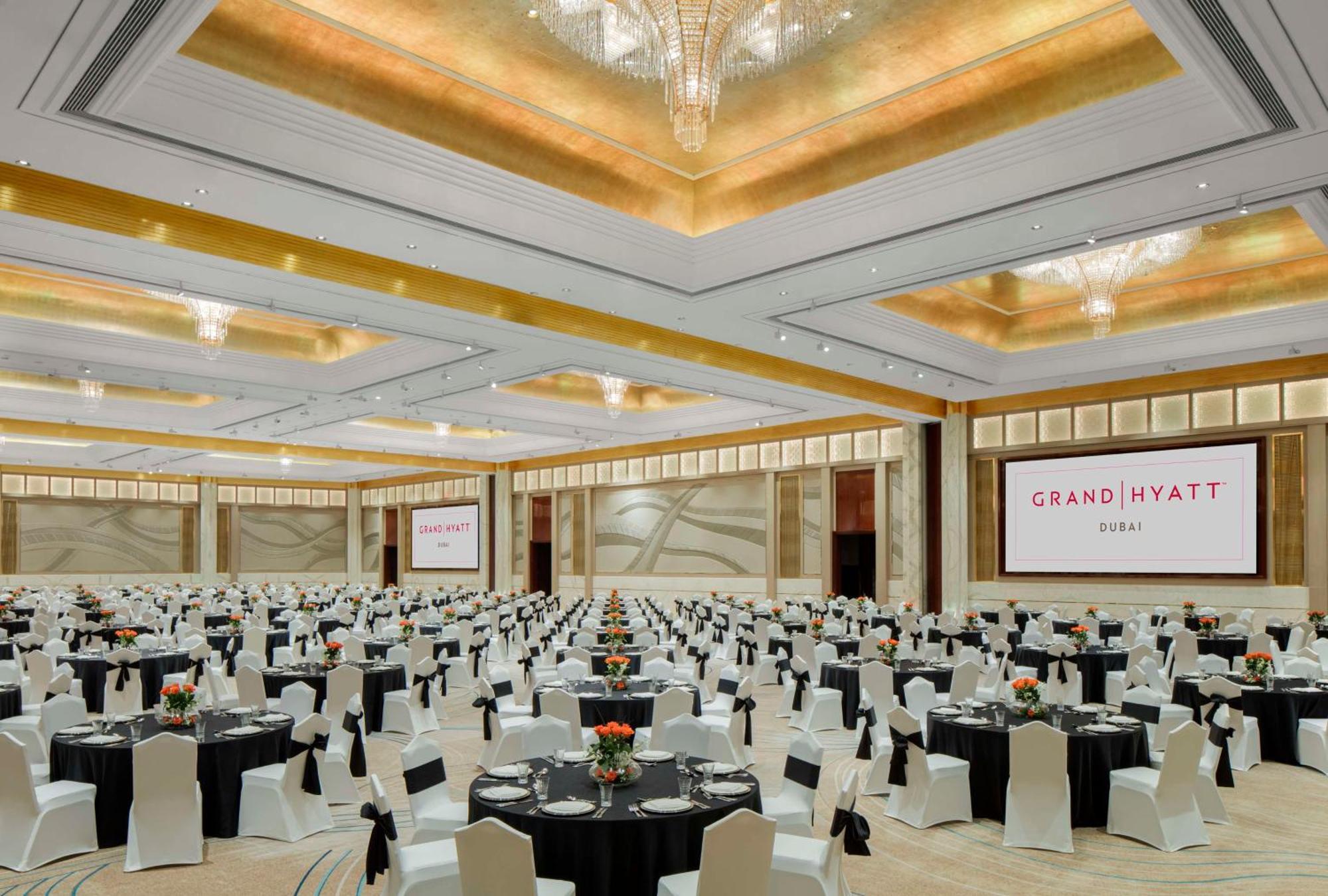 Hotel Grand Hyatt Dubai Esterno foto The image shows a large banquet hall set up for an event at the Grand Hyatt. The room is spacious with elegantly designed decor, featuring high ceilings and chandeliers. Numerous round tables are arranged throughout the space, each covered with black