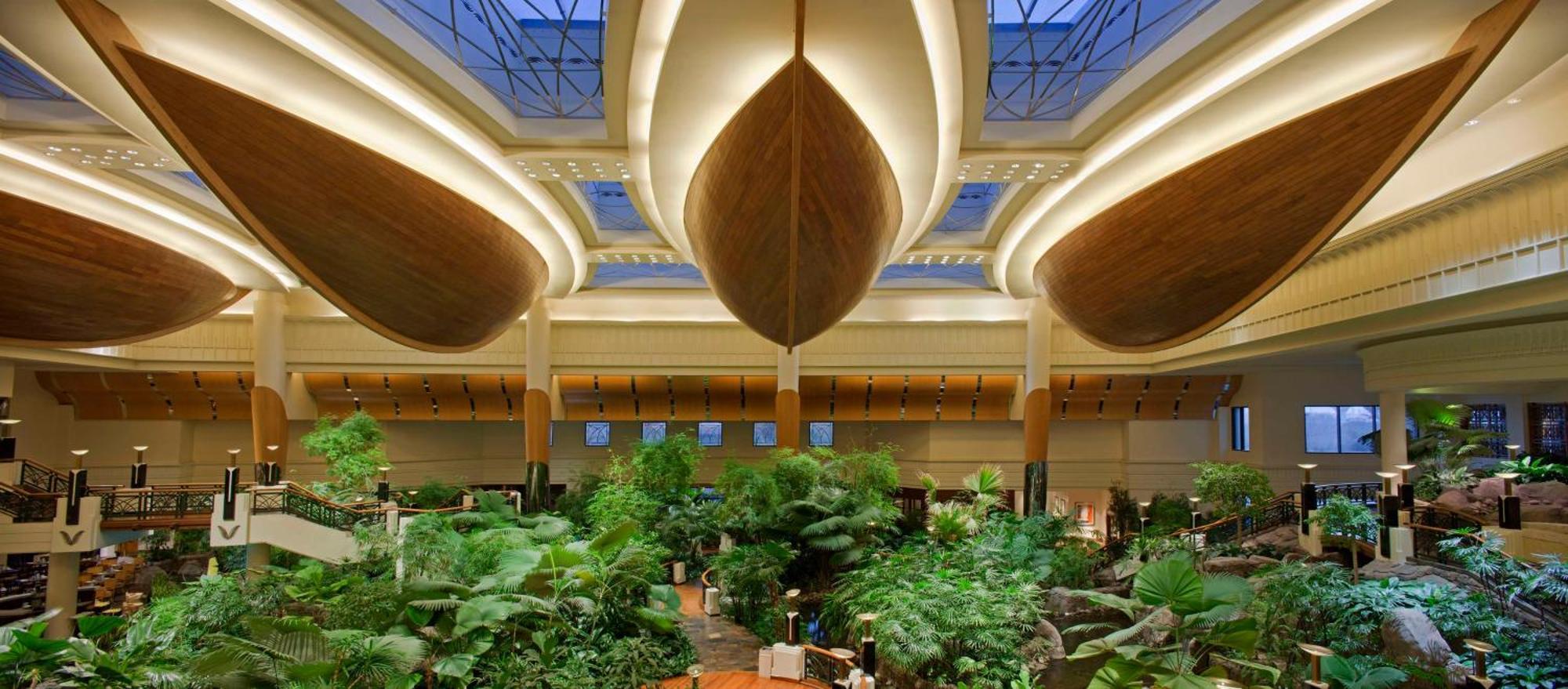 Hotel Grand Hyatt Dubai Esterno foto The photo showcases an indoor space that features a lush, tropical garden with abundant greenery, including various plants and trees. The architecture above is striking, with large, curved wooden structures reminiscent of boat hulls, which adds a uni